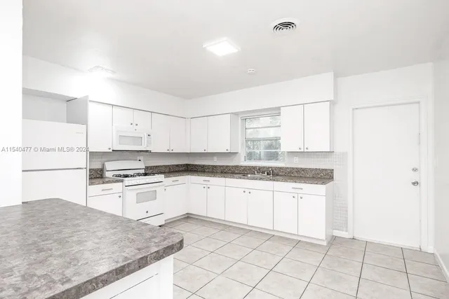 a kitchen with granite countertop white cabinets and white appliances