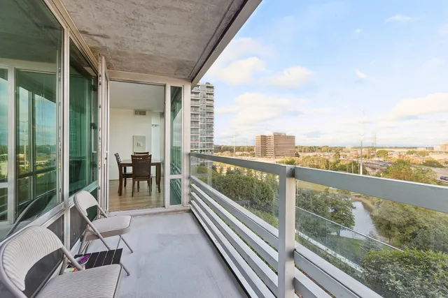 a view of a city from a balcony with chairs