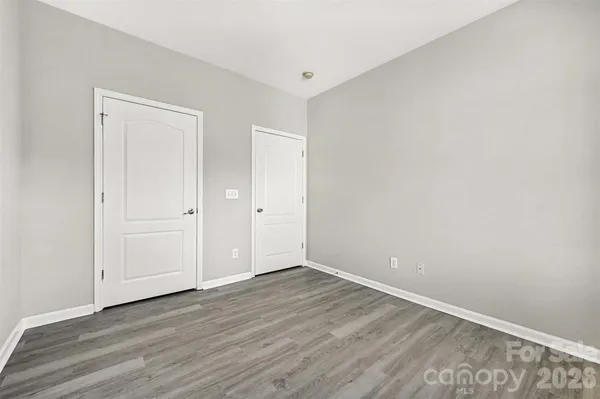 a view of an empty room with wooden floor and closet