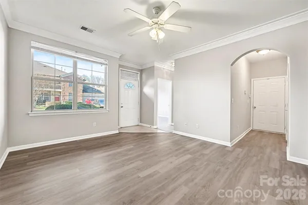 a view of an empty room with window and wooden floor