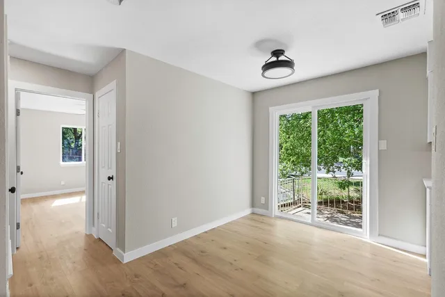 a view of a hallway to a livingroom with wooden floor and a window