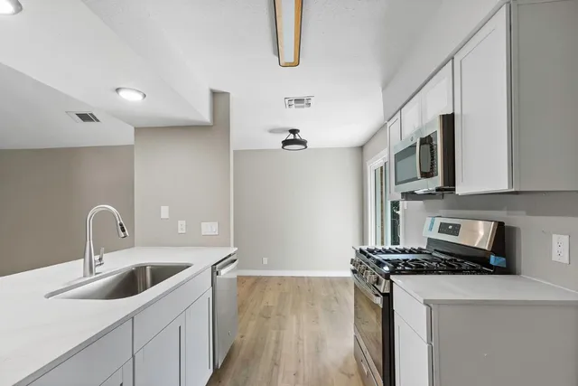 a kitchen with stainless steel appliances a sink a stove top oven a counter space and cabinets