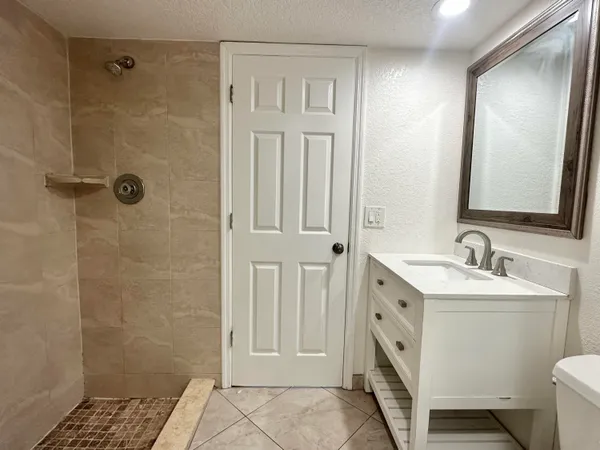 a bathroom with a double vanity sink a toilet and shower