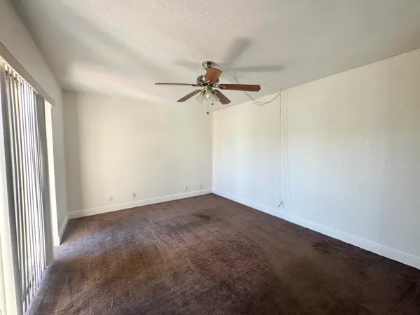 an empty room with a window and a fan
