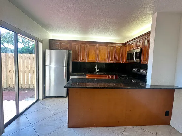 a kitchen with kitchen island a sink a refrigerator and a stove top oven