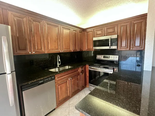 a kitchen with stainless steel appliances granite countertop a stove a sink dishwasher and a microwave oven with cabinets