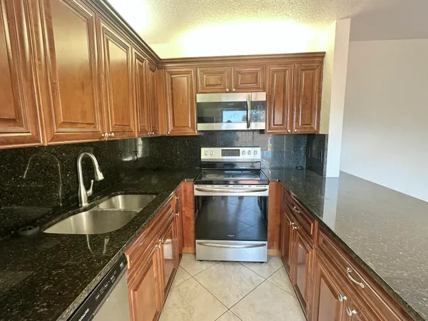 a kitchen with granite countertop a sink stove and cabinets