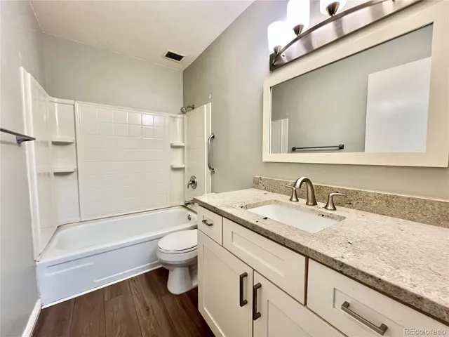 a bathroom with a granite countertop sink a toilet and a large mirror