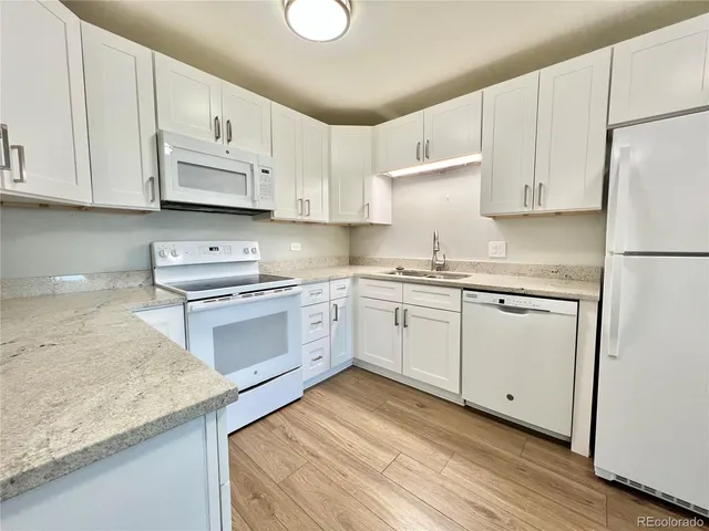 a kitchen with granite countertop white cabinets and white appliances