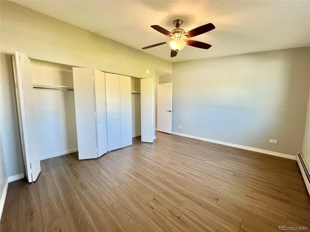 an empty room with wooden floor and a ceiling fan