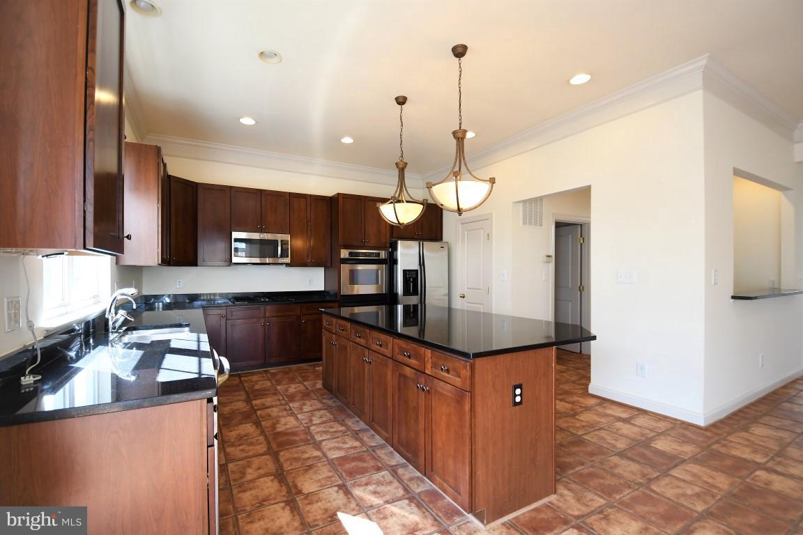 12845 Victory Lakes Loop Bristow, VA 20136 - Photo 4 of 27 a kitchen with stainless steel appliances kitchen island granite countertop a stove a sink and a refrigerator