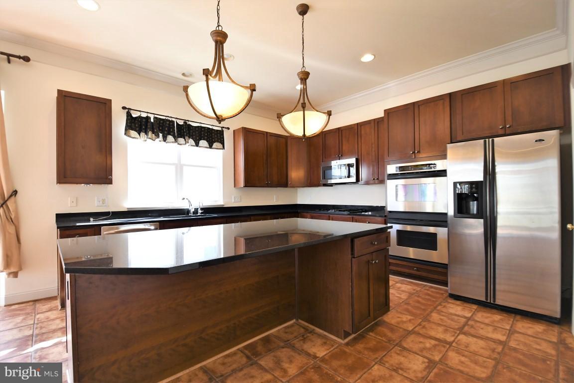 12845 Victory Lakes Loop Bristow, VA 20136 - Photo 5 of 27 a kitchen with stainless steel appliances granite countertop a sink a microwave a stove and a refrigerator