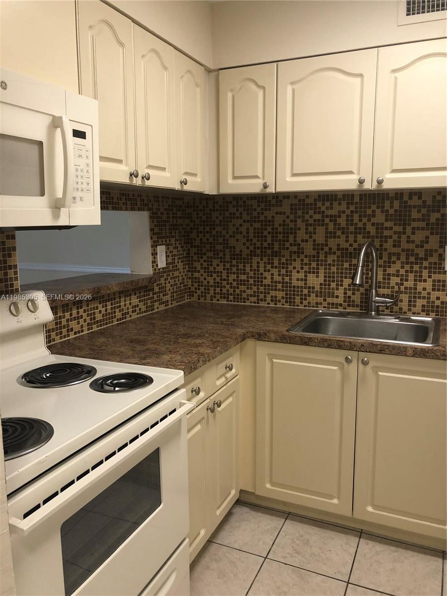 9467 Southwest 76th Street, Unit Q3 Miami, FL 33173 - Photo 3 of 18 a kitchen with granite countertop white cabinets and white appliances
