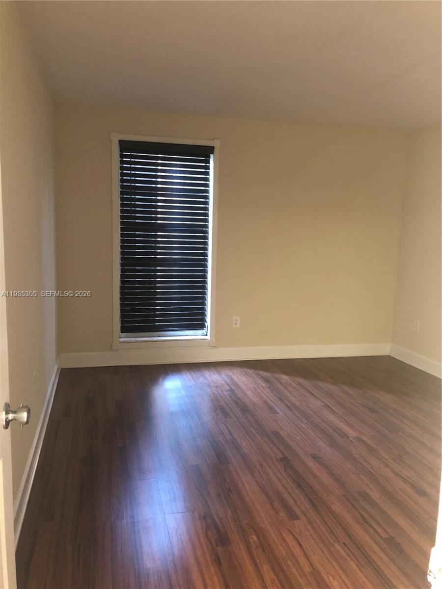 9467 Southwest 76th Street, Unit Q3 Miami, FL 33173 - Photo 10 of 18 an empty room with wooden floor and windows