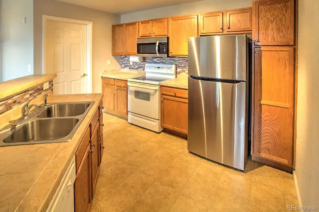 a kitchen with stainless steel appliances granite countertop a refrigerator a stove a sink dishwasher and a refrigerator with wooden floor