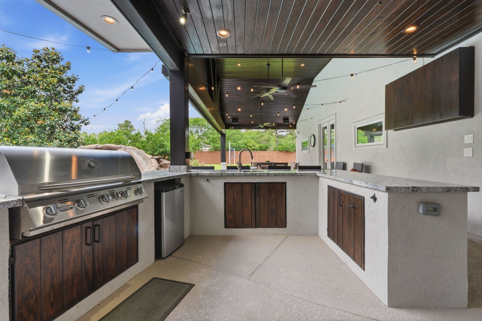 18 Dusk Valley Court Spring, TX 77379 - Photo 44 of 50 Outdoor kitchen with a built-in grill, refrigerator, sink, granite counter tops and storage. Custom cabinet for a TV. The perfect outdoor party set-up!