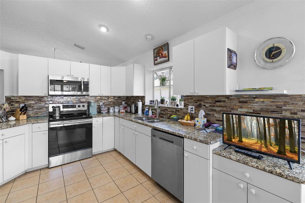 14462 Tamarind Loop Spring Hill, FL 34609 - Photo 5 of 28 a kitchen with granite countertop a stove sink and cabinets