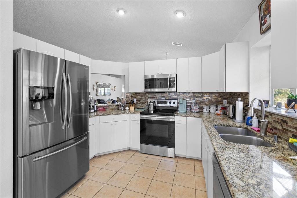 14462 Tamarind Loop Spring Hill, FL 34609 - Photo 6 of 28 a kitchen with stainless steel appliances granite countertop a refrigerator sink and stove