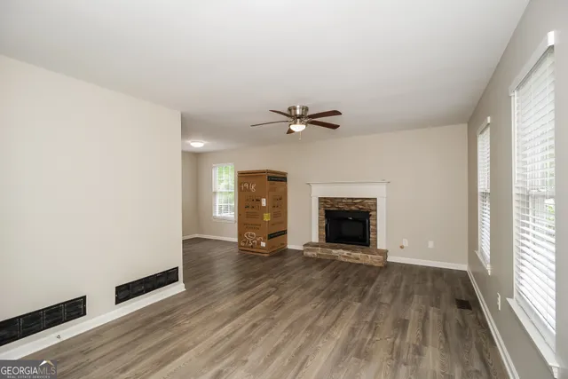 a view of an empty room with a window and wooden floor
