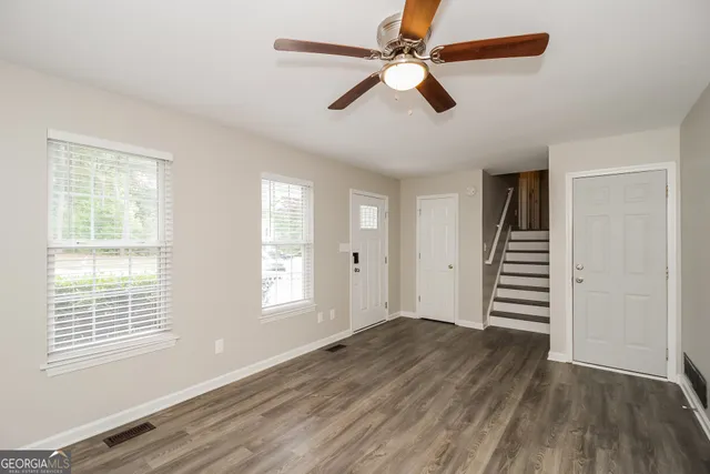 a view of empty room with wooden floor and fan