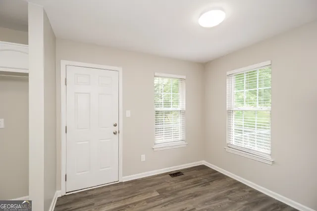 an empty room with wooden floor and windows