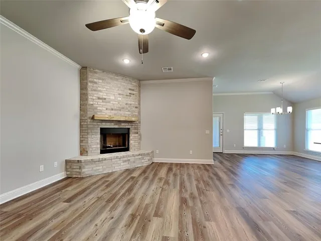 an empty room with wooden floor fireplace and windows