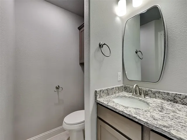 a bathroom with a granite countertop sink toilet and a mirror