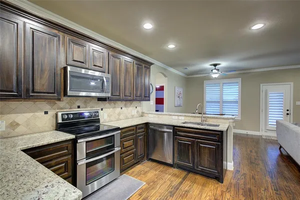a kitchen with stainless steel appliances granite countertop a stove a sink and a microwave