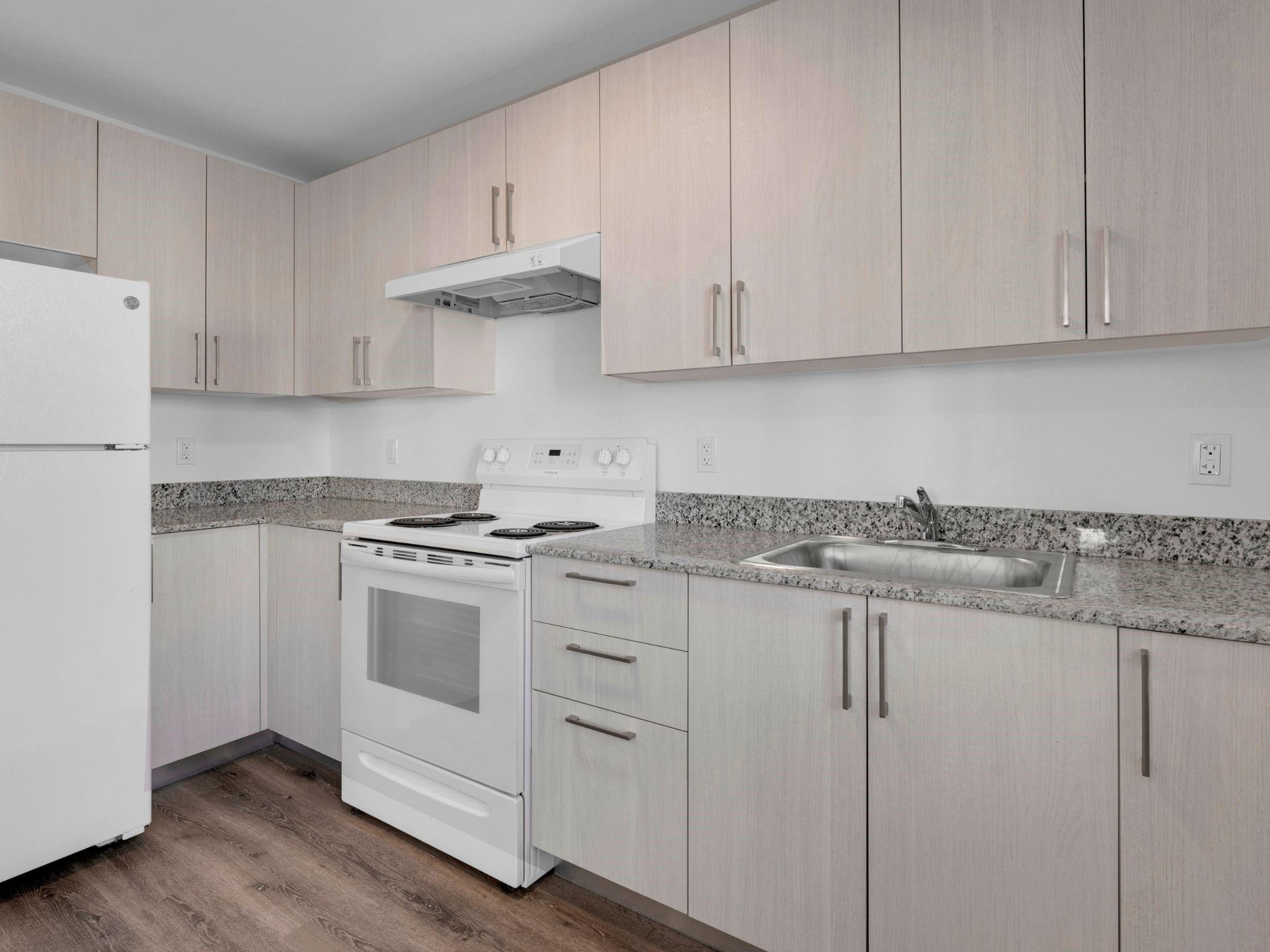 2130 Northwest 37th Street, Unit STUDIO Miami, FL 33142 - Photo 4 of 17 a kitchen with granite countertop white cabinets and white appliances