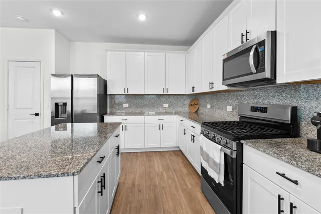 a kitchen with granite countertop a sink dishwasher stove and refrigerator with wooden floor
