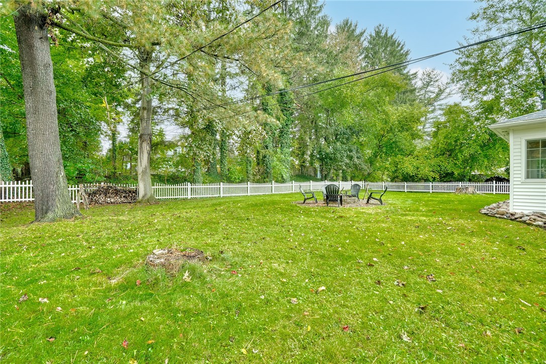 255 Fairport Road East Rochester, NY 14445 - Photo 25 of 26 Mature trees frame a spacious, fully fenced lawn perfect for outdoor activities and relaxation.