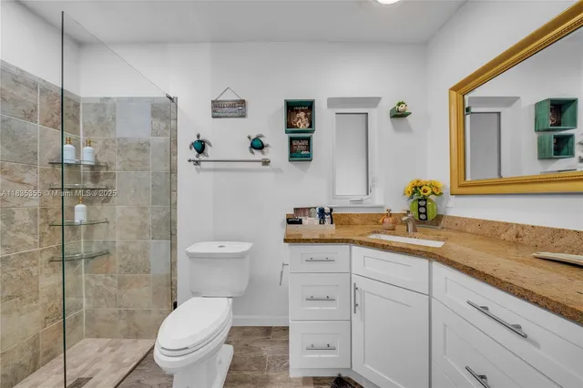 a bathroom with a granite countertop sink a toilet and shower
