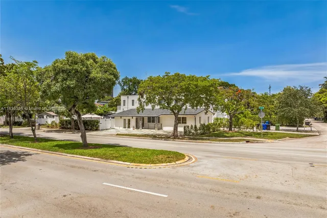 a view of a big house with a big yard and large trees
