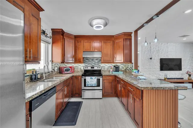 a kitchen with stainless steel appliances granite countertop a stove a sink and a microwave