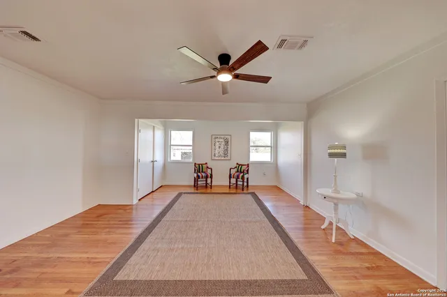a large bedroom with wooden floor and a ceiling fan