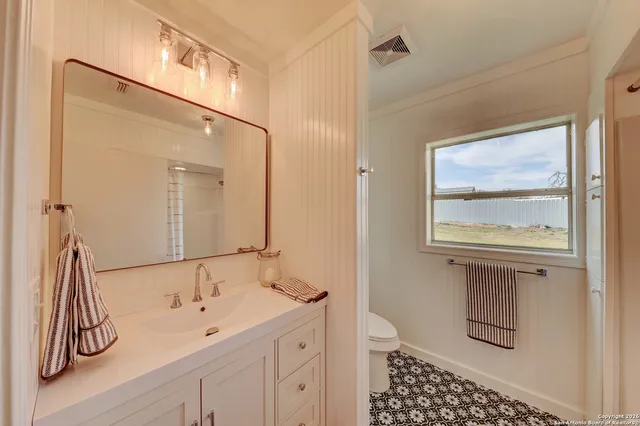 a bathroom with a granite countertop sink a mirror and shower