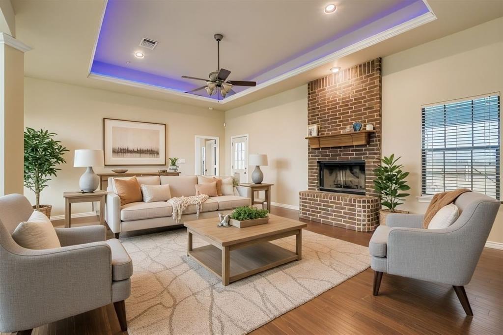 6025 Ge Horton Road Justin, TX 76247 - Photo 4 of 40 Living area featuring a raised ceiling, wood finished floors, a brick fireplace, and ceiling fan