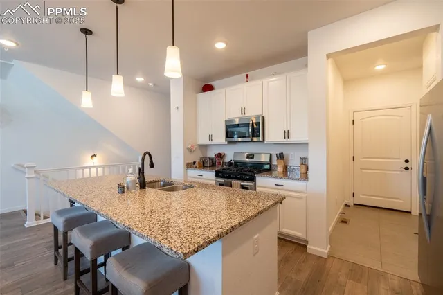 a kitchen with kitchen island granite countertop a sink a counter top space appliances and cabinets