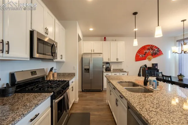 a kitchen with stainless steel appliances granite countertop a sink a stove and a refrigerator