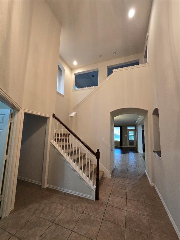 213 Willet Court Little Elm, TX 75068 - Photo 8 of 28 Stairs featuring a high ceiling, arched walkways, tile patterned floors, and recessed lighting