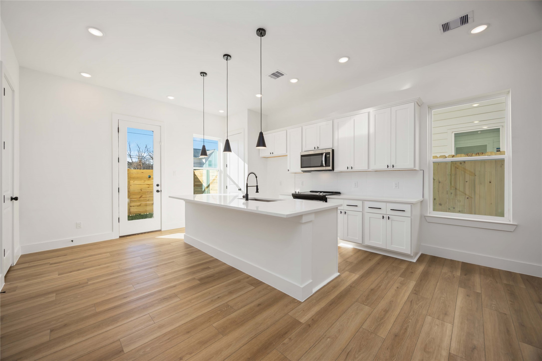 1466 Ferguson Way, Unit B Houston, TX 77088 - Photo 10 of 28 a large kitchen with white cabinets stainless steel appliances a sink and wooden floor