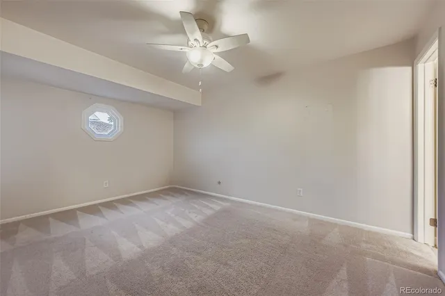 an empty room with a chandelier fan and windows