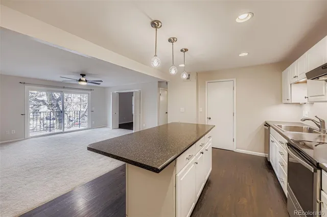 a kitchen with granite countertop a stove a sink a refrigerator dining table and chairs