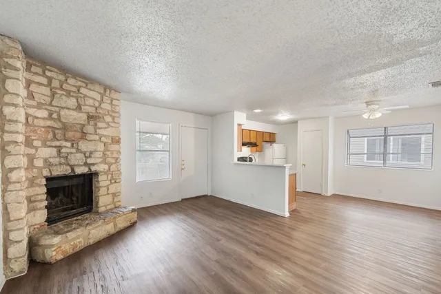 an empty room with wooden floor fireplace and windows