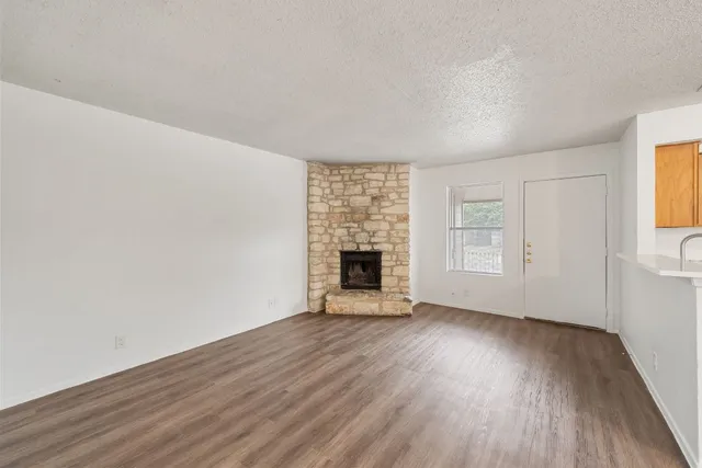 an empty room with wooden floor fireplace and windows
