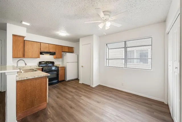 a kitchen with stainless steel appliances granite countertop a stove a sink dishwasher and a refrigerator with wooden floor