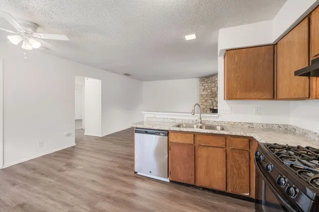a kitchen with granite countertop a sink a stove cabinets and wooden floor