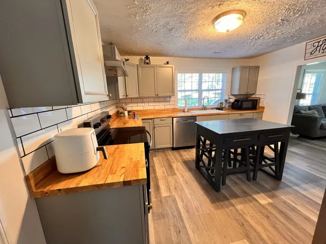 a kitchen with a sink a stove and wooden floor