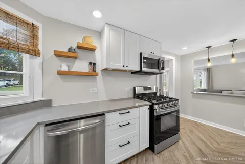 a kitchen with stainless steel appliances white cabinets and stove top oven