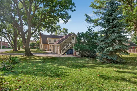a view of a house with a big yard and large trees